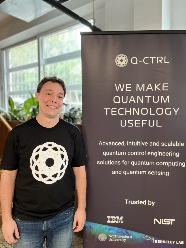 Donland White in 2025 standing next to a banner for his employer Q-CTRL