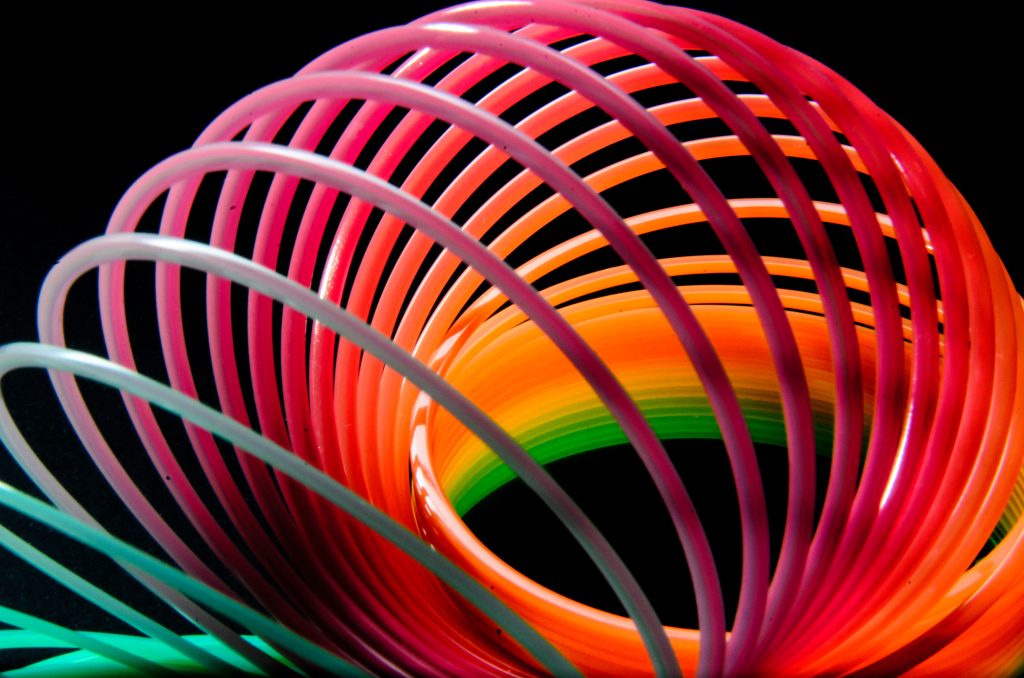 Close up of a multi-coloured plastic slinky spring uncoiling at one end