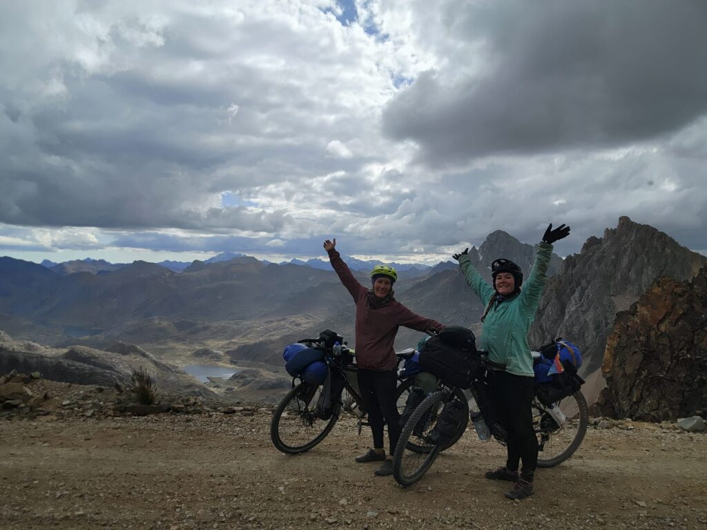 Gemma and her sister Kaylie standing next to their bikes on the Peru great divide tcycle trail overlooking mountains.